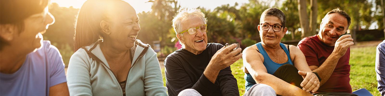 Male and female senior living residents sitting outdoors in the grass