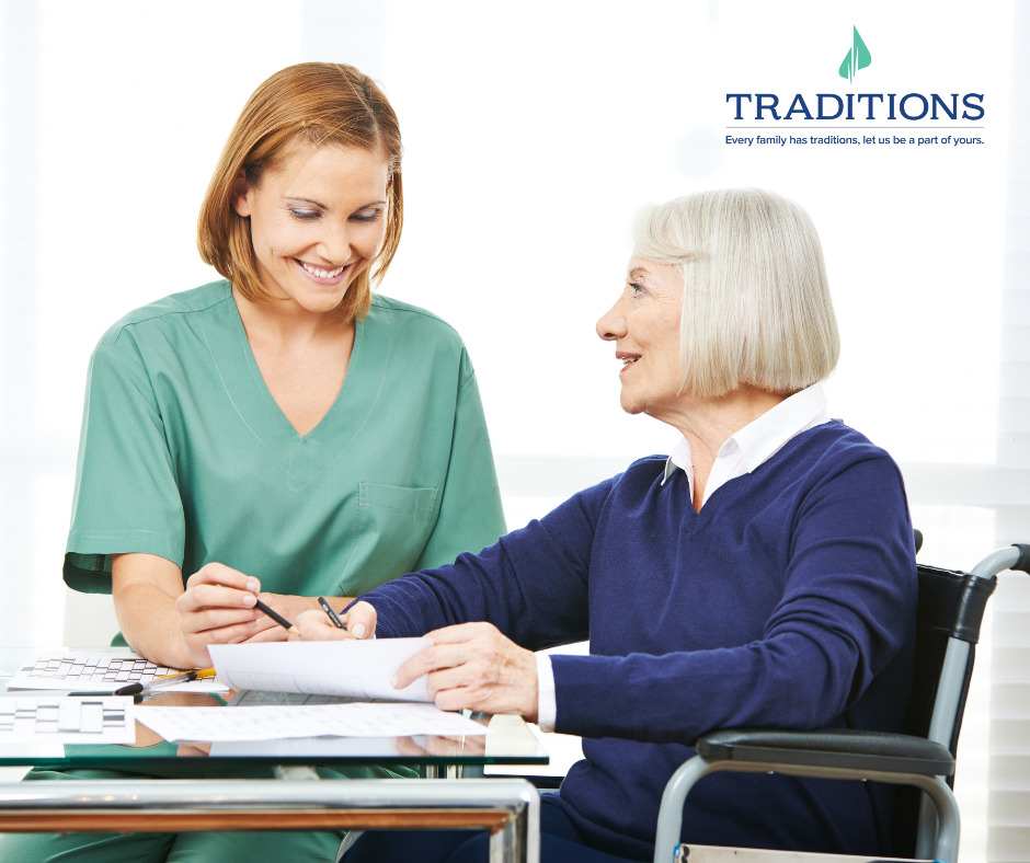 A woman in green scrubs works with an elderly woman in blue