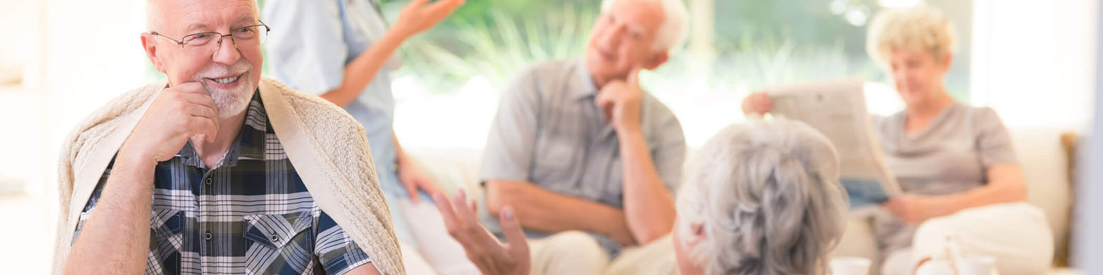 Male and female senior living residents gathered in a community room while socializing